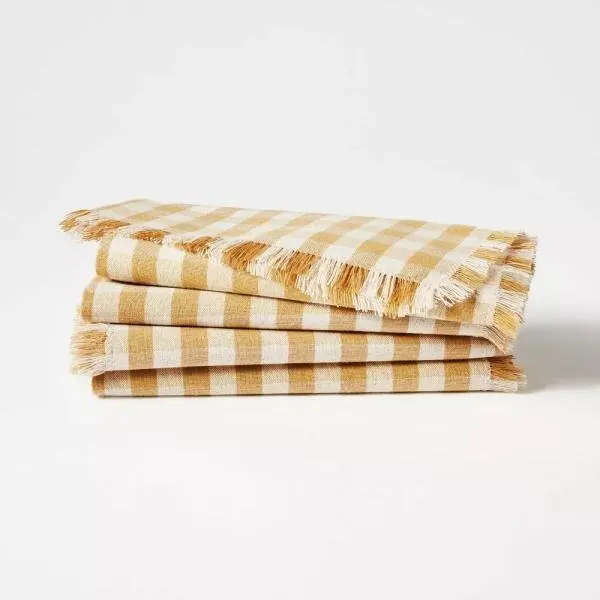 Servilletas de tela paquete de 4. Patrón de cuadros vichy tostados sobre fondo blanco. Hecho de mezcla de algodón y lino, bordes con flecos. Forma cuadrada de 18 pulgadas