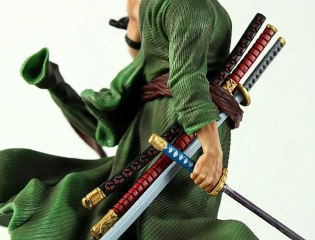 Figura coleccionable de Roronoa Zoro de la serie One Piece, en pose de combate con capa verde, faja roja y espadas, base de roca decorativa de 27 cm de alto, para vitrina o escritorio, foto 3 de 5