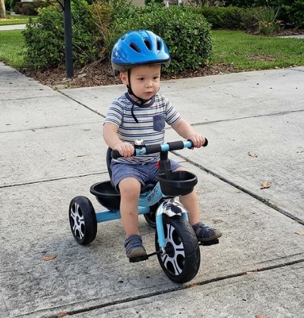 Triciclo infantil de color azul y asiento negro, con tres ruedas, dos canastas de almacenamiento, timbre, manubrio con agarres y pedales, ideal para niños pequeños que quieren aprender a pedalear, foto 2 de 6